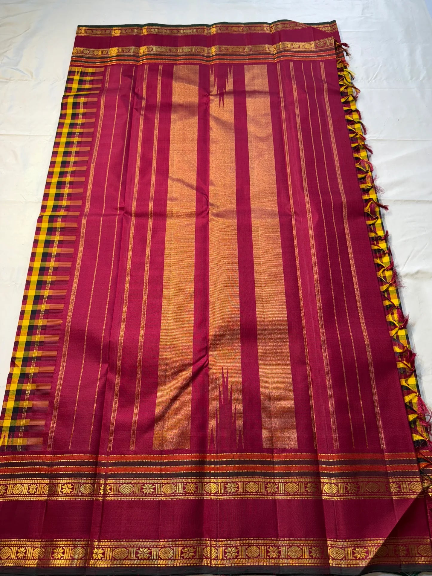 Manjal Maroon Kattam – Pure Kanchipuram Silk Saree
Mustard & Maroon Body with Traditional Multi-Color Checks
Korvai Borders with Floral-Star Zari & Temple Tips
Grand Maroon Pallu with Gold Zari Stripes & Tassels
Silk Mark Certified | ships in 2 weeks