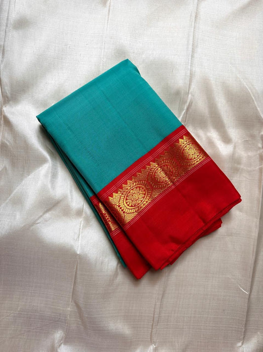 Rama green handloom Kanchipuram silk saree fully spread out, featuring rich red kaal erangina pallu and traditional gold zari motifs.
