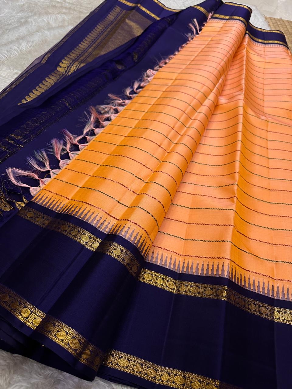 Peach Veldhari ✨ – Pure Kanchipuram Silk Saree with Royal Blue Border & Pallu

Peach-Orange Veldhari Striped Body with Subtle Green & Maroon Accents

Royal Blue Korvai Border with Intricate Gold Zari Motifs

Majestic Royal Blue Zari Brocade Pallu