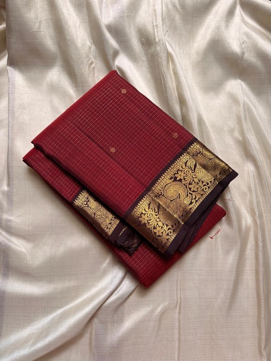 Mantra – Ruby Red coffee brown Kanchipuram Silk Saree with zari Checks with small buttas all over and Antique Peacock zari Border  showcasing regal peacocks and floral vines. A richly detailed pallu completes this heritage Zari kattam