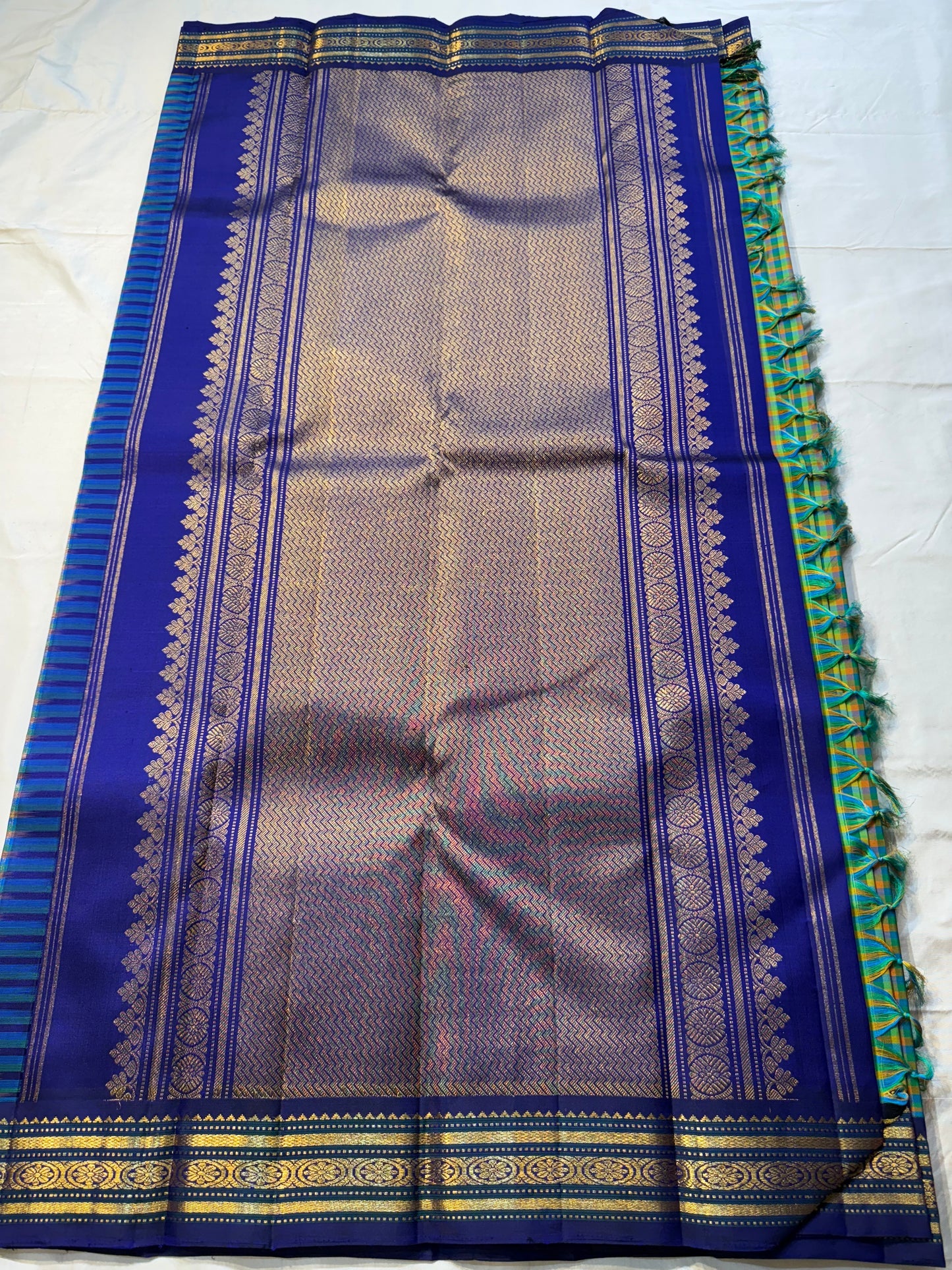 Mayil Pachai Kattam
Pure Kanchipuram Silk Saree – Peacock Green & Mustard Micro Checks
Royal blue korvai borders with gold floral zari detailing
Grand zari pallu with traditional zari weaving
Ships in two weeks free shipping, silk mark certified