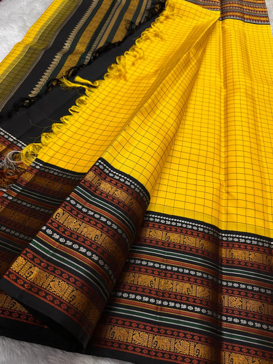 Marigold Mani Kattam – Pure Kanchipuram Silk Saree
Vibrant marigold yellow body with classic kattam checks
black borders with elephant & floral zari motifs
Rich black pallu adorned with green & zari stripes . Silk Mark Certified, delivery in 2 weeks