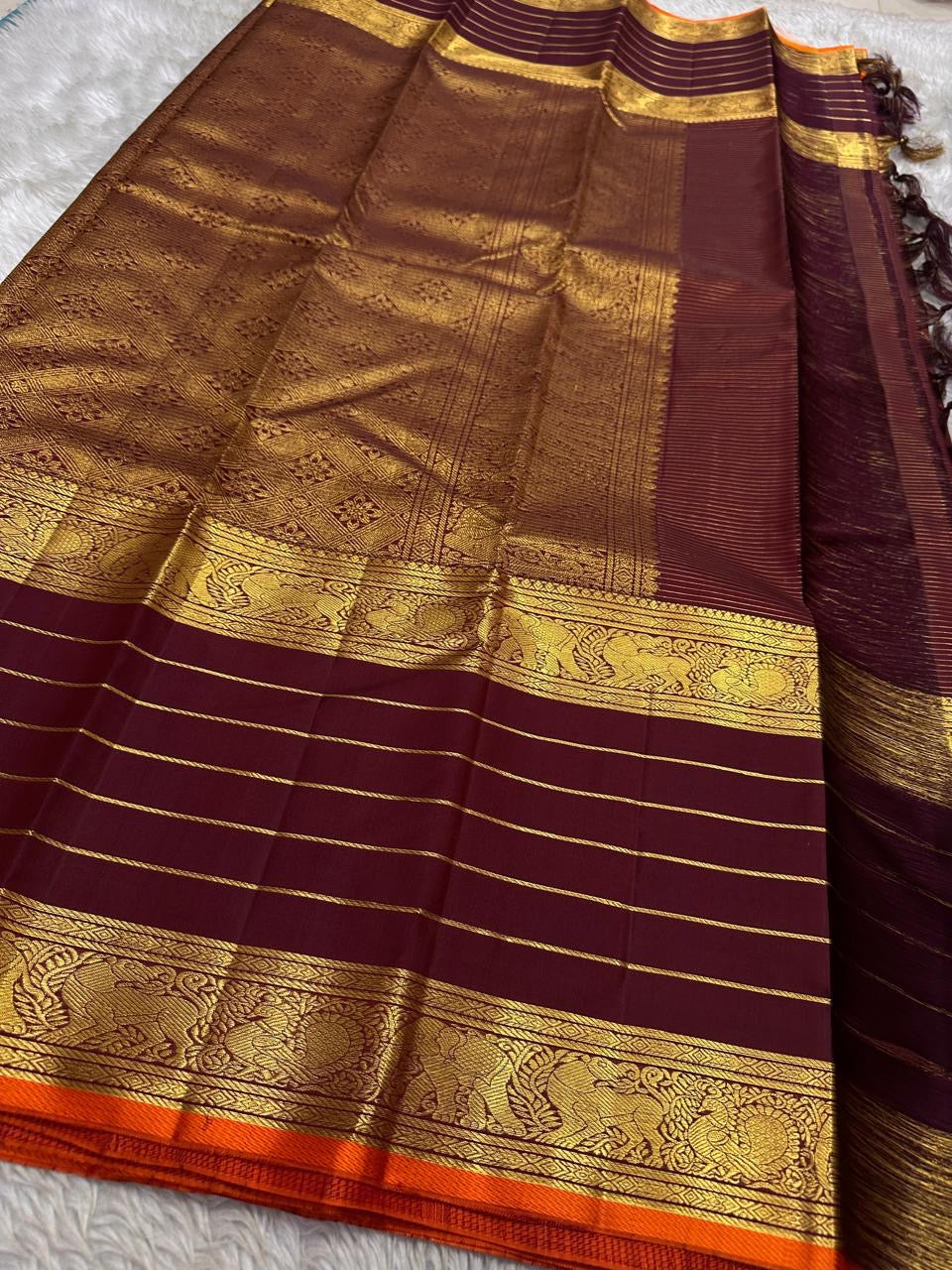 Full layout of maroon Kanchipuram silk saree with gold horizontal stripes, orange selvedge and grand zari pallu and borders.