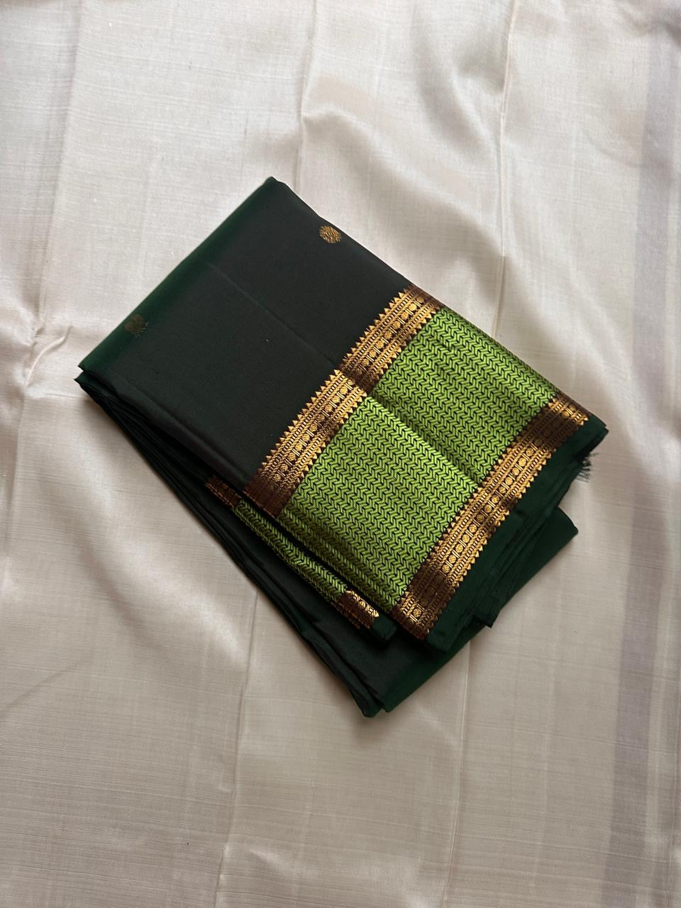 Pachai Maragatham — Pure Kanchipuram Silk Saree
Deep pachai (forest green) body with gold chakram buttas and maragatham chevron zari borders, finished with a coffee-brown brocade pallu.
Silk Mark Certified • Blouse Stitching Available ($30) • Free Shippin