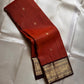 Kavi — oosi  kattam Pure Kanchipuram Silk Saree

Burnt Orange (saffron–rust) body
Deep coffee-maroon contrast border with grand antique-gold zari
Rich brocade pallu; peacock & floral vines in the border
Silk Mark Certified