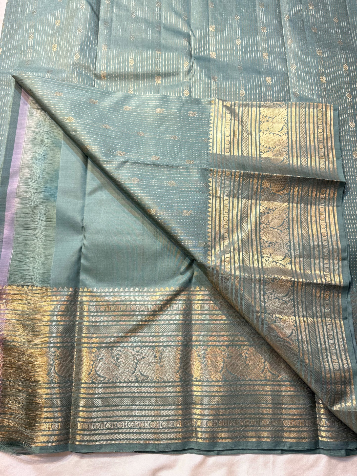 Muted sea-jade/duck-egg green body with fine oosi (pin) stripes

All-over tiny rosette/coin buttas for a soft shimmer

Silk Mark Certified | Free Shipping within USA | Ships in Two Weeks. Blouse Stitching ($30)