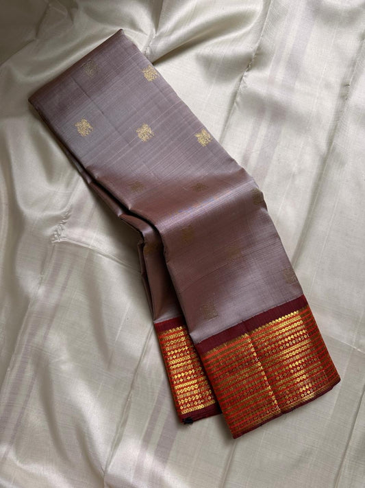 Taupe Glow – Pure Kanchipuram Silk Saree
Ash Taupe Grey Body with Lilac Undertone
Intricate Devadatta Flying Horse Motif in Zari
Deep Maroon Varisaipet Border with Rich Contrast
Grand Zari Pallu with Thazampoo Temple Motifs