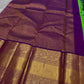 This pure silk Kanchipuram saree features a radiant shot color blend of green, gold, and blue, adorned with delicate zari buttas. A regal royal purple rettapet border and an elaborate peacock motif pallu complete this timeless drape — perfect for festive