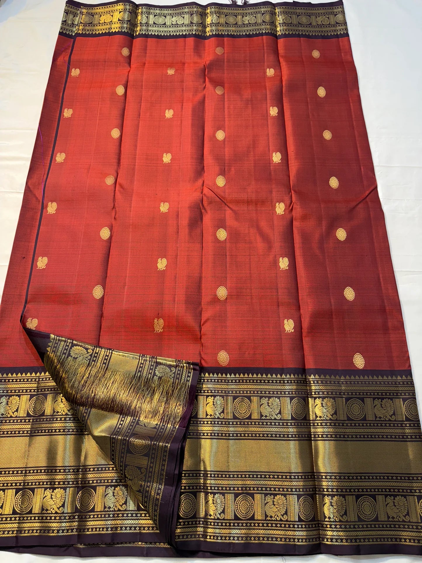 Aruna Mayil – Pure Korvai Kanchipuram Silk Saree

Brick red body with zari rosette buttas

Grand coffee-brown korvai border & pallu with peacock panels, medallions & temple teeth in rich gold zari

Silk Mark Certified | Blouse Piece Included | Fall & Pico