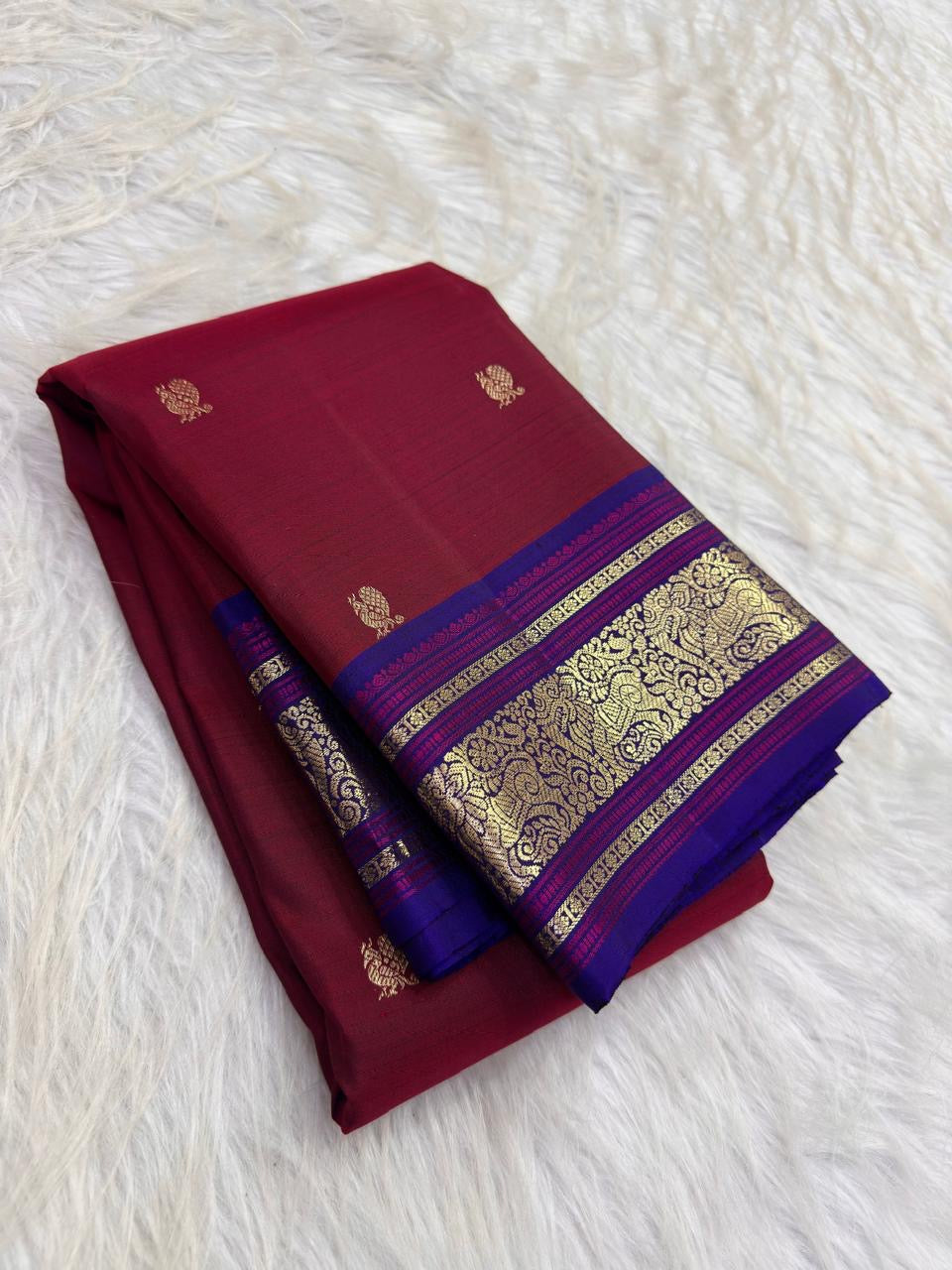 Detail of the woven silk and gold zari border of arakku red pure silk kancheepuram peacock butta saree with indigo violet border