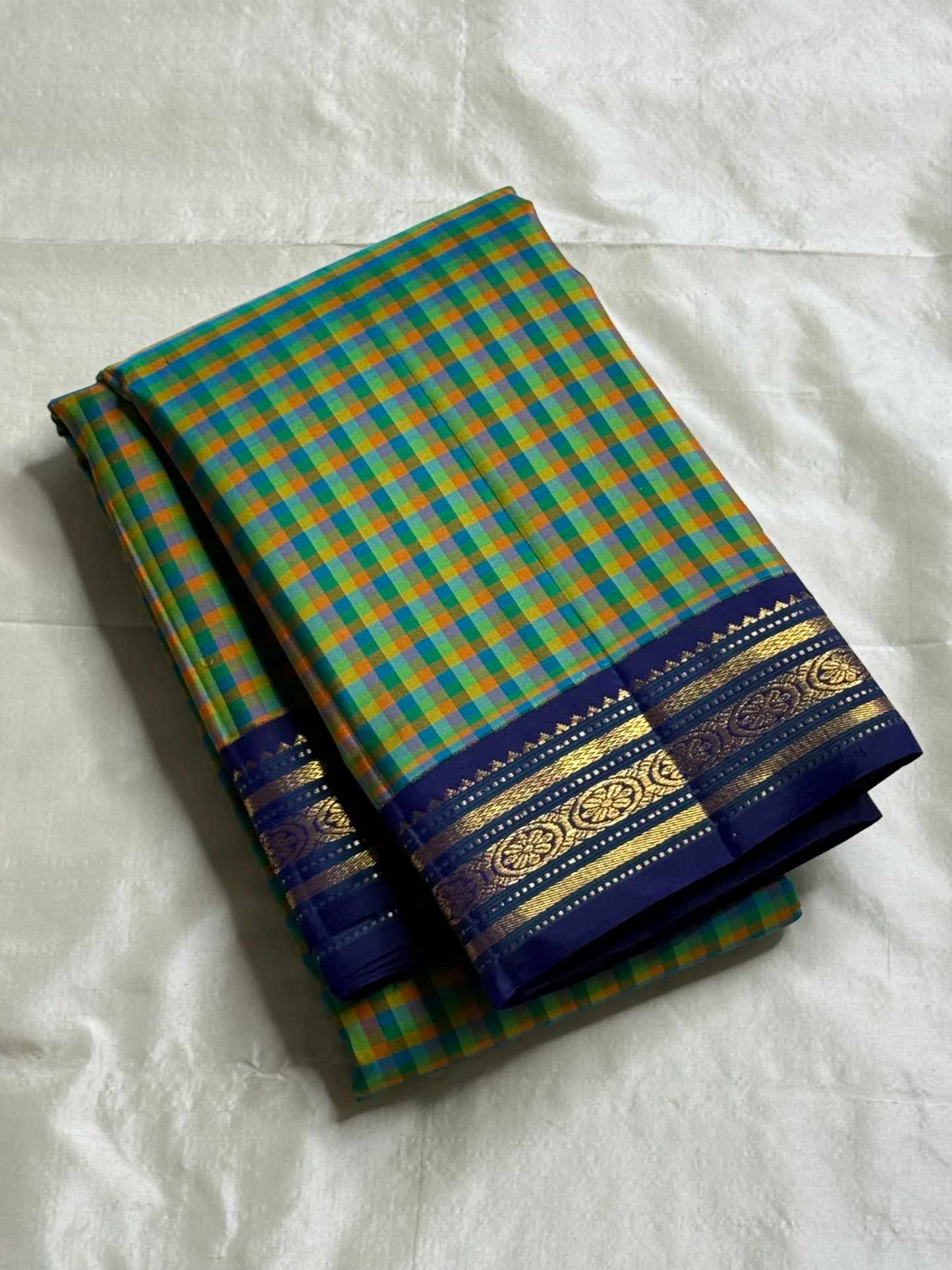 Mayil Pachai Kattam
Pure Kanchipuram Silk Saree – Peacock Green & Mustard Micro Checks
Royal blue korvai borders with gold floral zari detailing
Grand zari pallu with traditional zari weaving
Ships in two weeks free shipping, silk mark certified