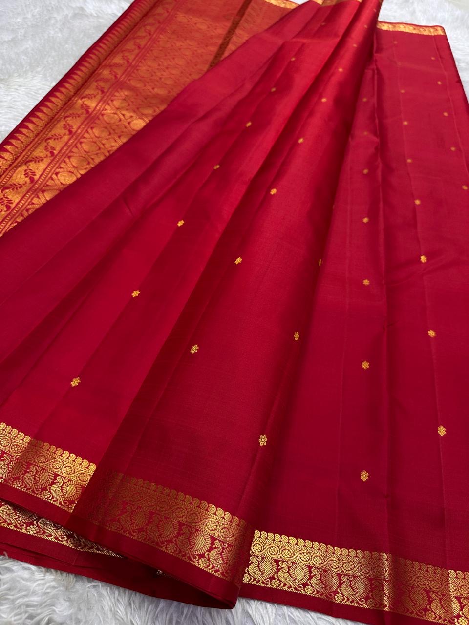 Mahima –red
A luminous red pure silk Kanchipuram drape adorned with delicate baby  kamalam buttas. The petite border features muthu seer and zari-woven elephants with floral vines. Its grand pallu showcases annams, golden grids, and Rudhraksham seer.