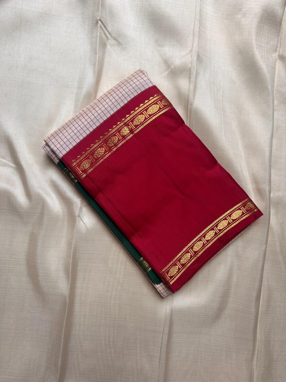 Ivory saree with fine red kattam checks and maroon zari border folded flat lay