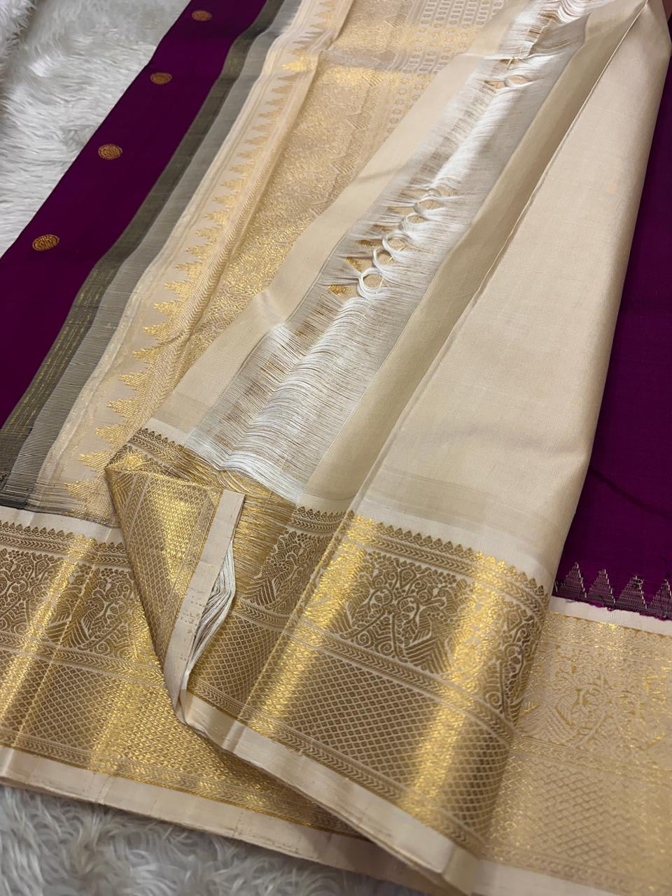 Varuni — Deep Purple & Magenta Shot Kanchipuram Silk Saree
Gold Zari Peacock Motifs on Luxurious Pure Silk
Antique Gold Korvai Border with Gandaberunda Design
Intricate Temple-Inspired Pillayar Moggu Detailing
Silk mark certified