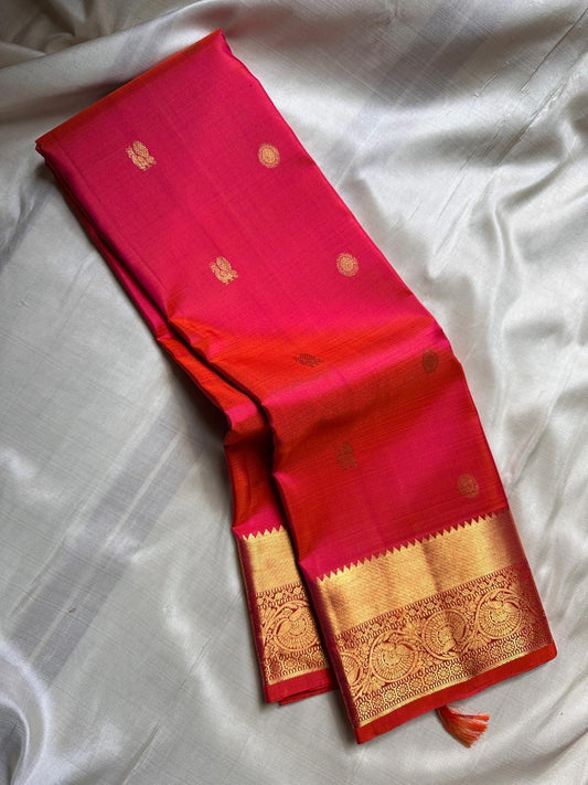 Agnika – Tomato orange shot Red Kanchipuram Silk Saree with Mayil Chakram Butta & Orange Border
Fiery and regal, Agnika is a pure Kanchipuram silk saree featuring a rich red body adorned with intricate Mayil Chakram buttas.