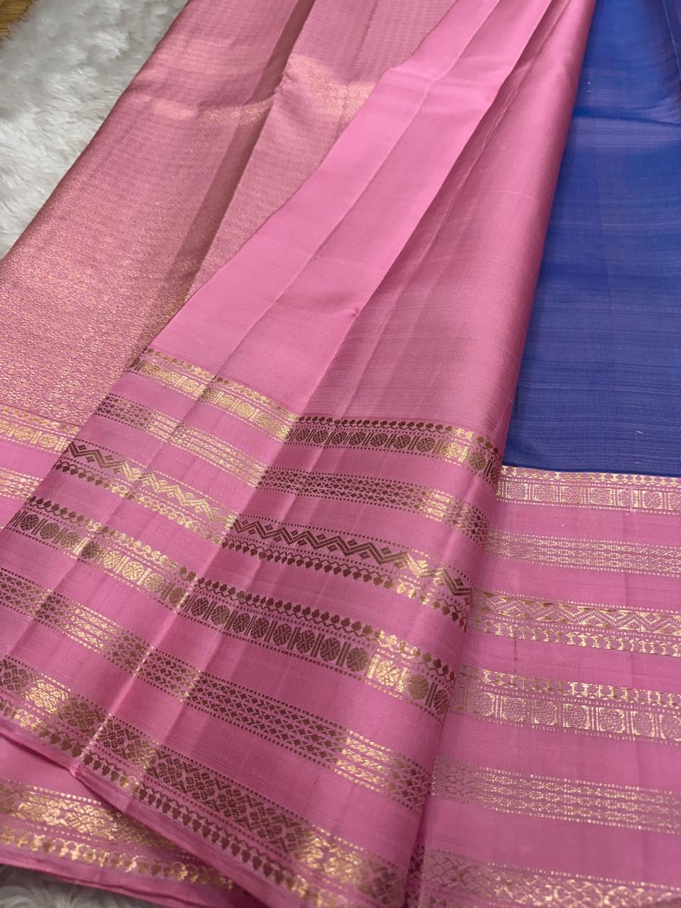 Ramyam, meaning pleasant and delightful, features a mesmerizing blue–purple shot body that shimmers with every movement. Its radiant pink korvai border and pallu, adorned with traditional Varisaipet zari stripes, add festive brilliance.silk mark certified