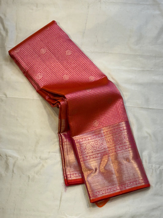 Peach Pink Flower Butta – Coral-pink shot body with micro checks & floral buttas

Handwoven Kanchipuram silk with delicate copper-pink zari work

Elegant floral vines on borders • grand rose-gold brocade pallu

Silk Mark Certified | Fall & Pico Done |