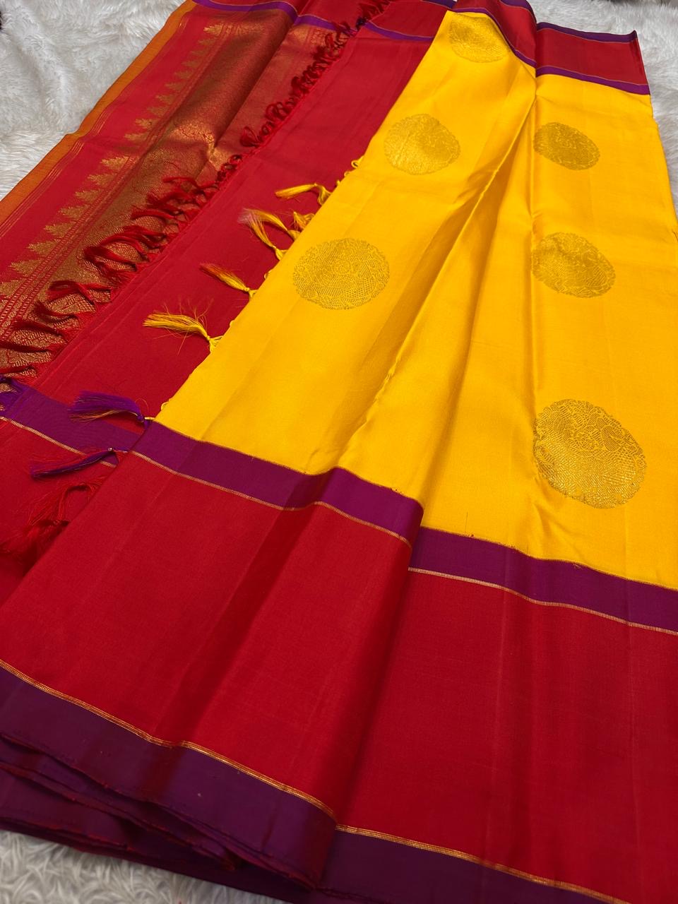 Mustard yellow and vermilion silk saree folded showing magenta contrast border