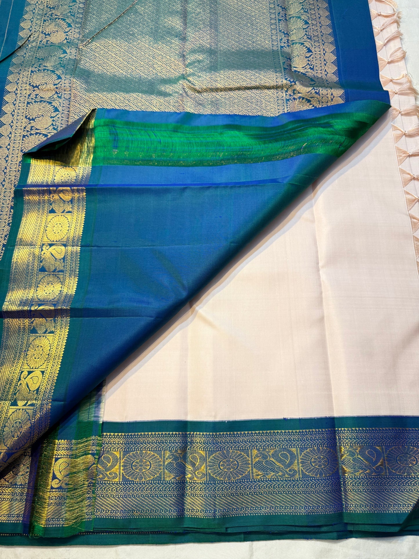 Mayilkazhuthu Shwetham — Pure Kanchipuram Silk Saree
Soft Ivory-Blush Body with Gold Zari Buttas & Peacock Blue-Green Border
Silk Mark Certified • Free Shipping within USA • Ships in Two Weeks