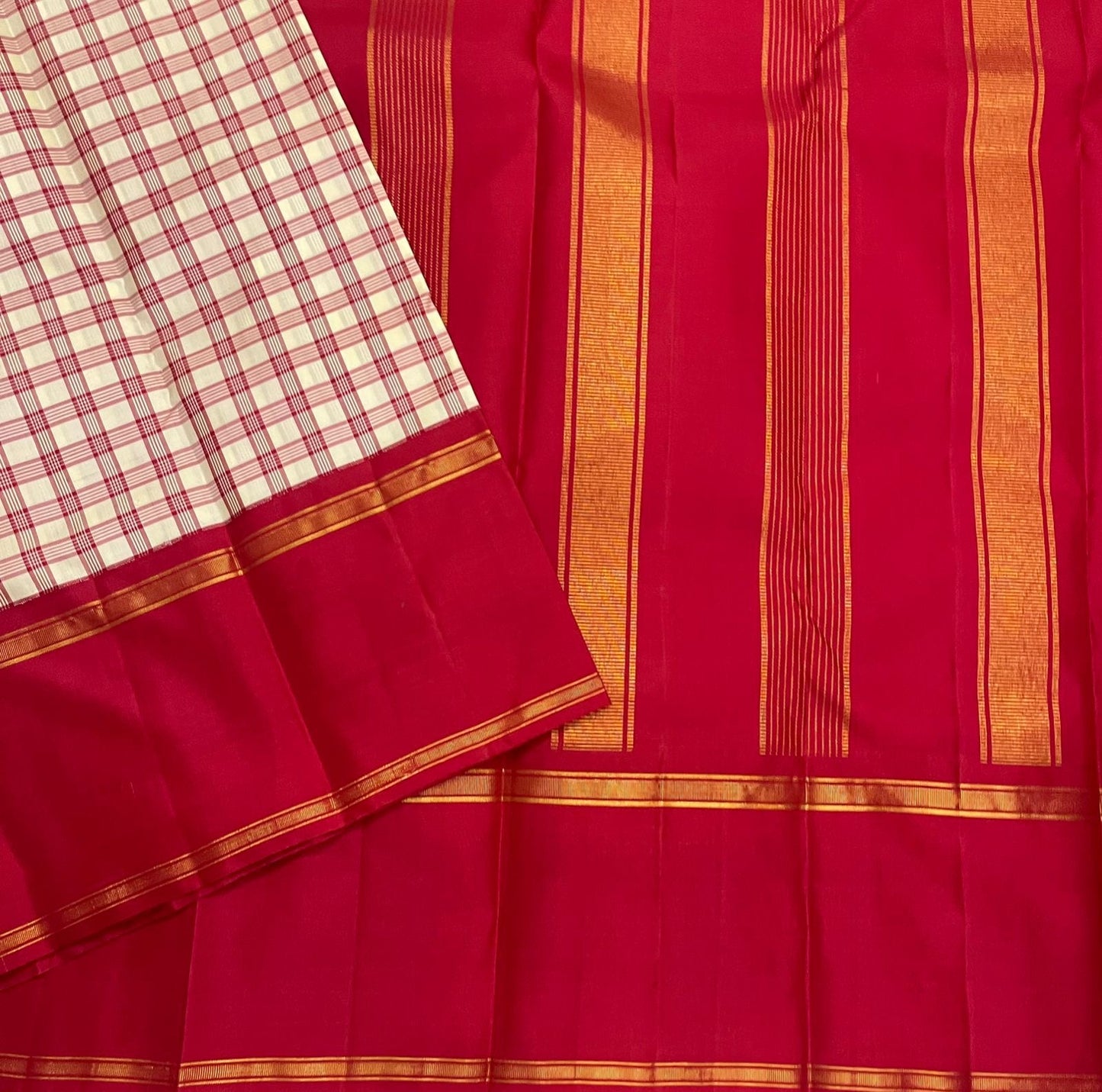 Close view of deep red pallu with vertical gold zari woven stripes and a matching border, next to the checked cream panel.