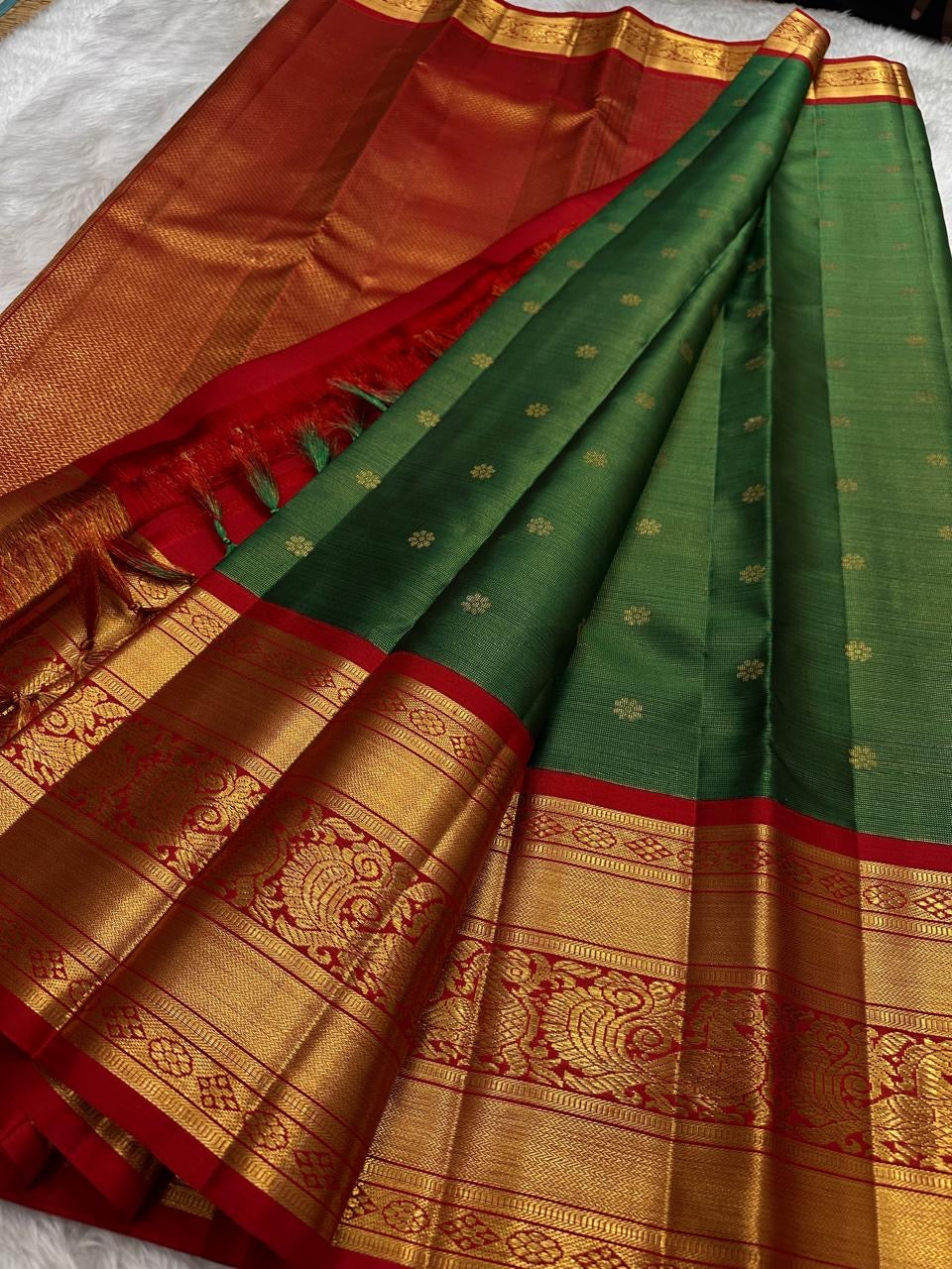 Decorative peacock-style border panel woven in gold zari on the red border.