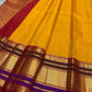 Draped view of mustard yellow Pure Kanchipuram Silk Saree showing zari border, maroon bands, and purple edge near the hem.