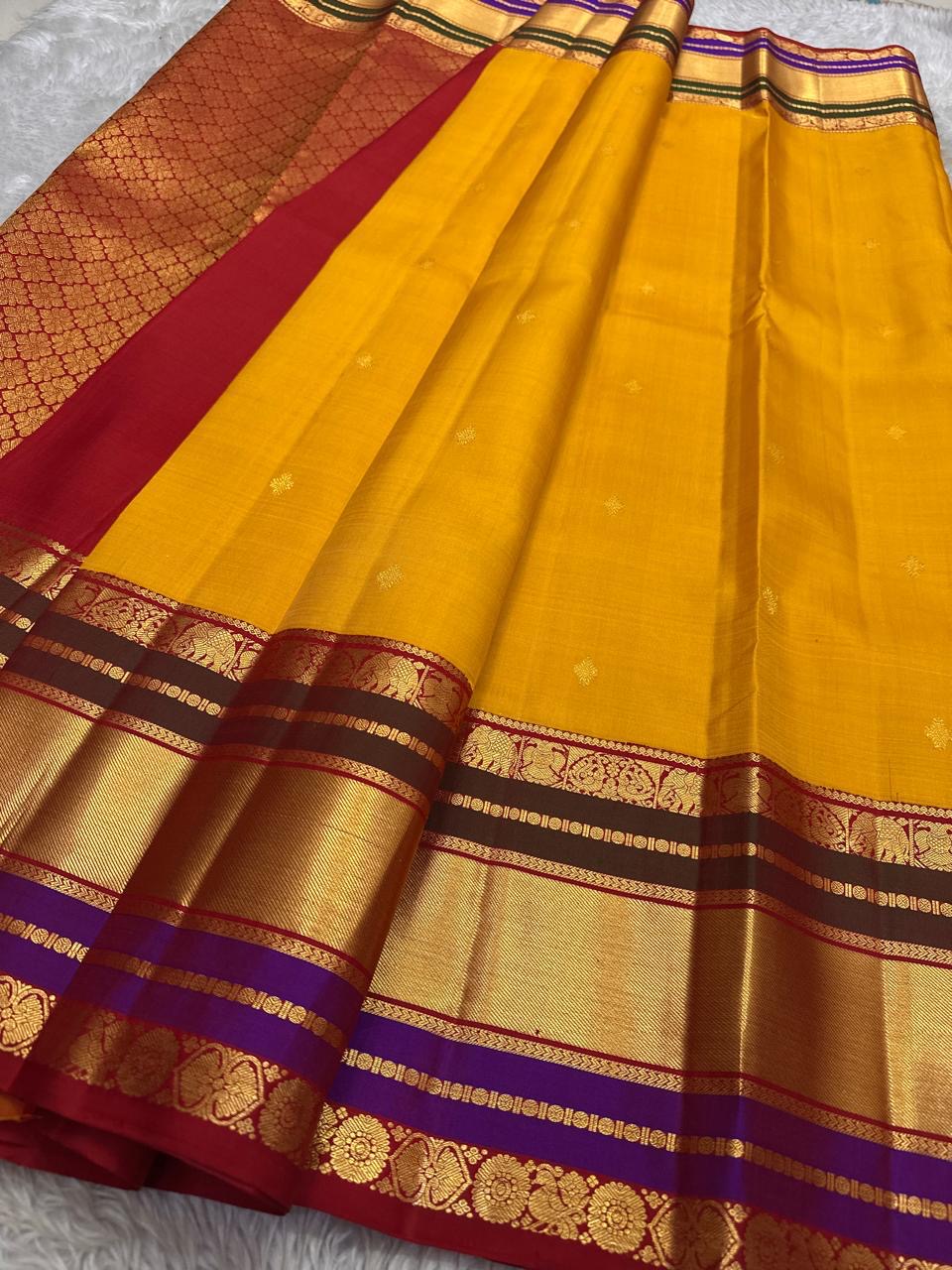 Draped view of mustard yellow Pure Kanchipuram Silk Saree showing zari border, maroon bands, and purple edge near the hem.