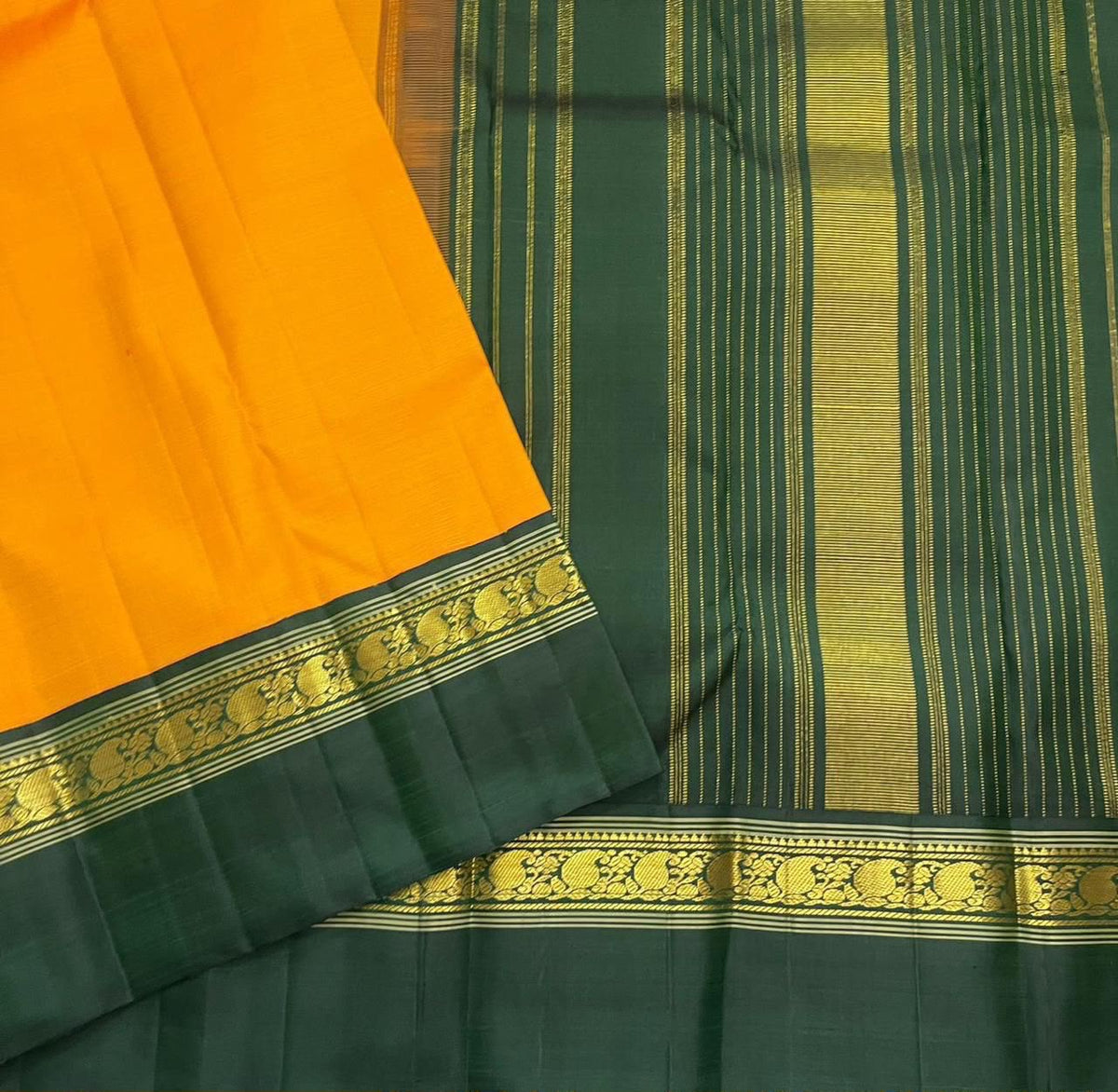 Folded saffron gold and deep green Pure Silk Kanchipuram Korvai saree showing contrast border