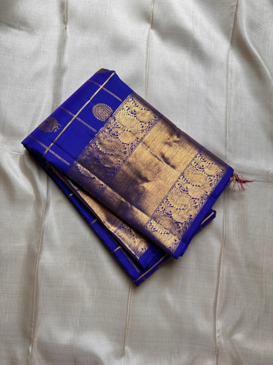 Kalyana Neelam Kattam — Kanchipuram Pure Silk

Deep royal neelam blue body with kattam (grid) checks & mayil buttas

Grand gold kaddi border with ornate paisley vines; rich zari pallu

Silk Mark Certified | Free Shipping within USA

Dispatch in 1 Week