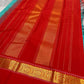 Rama green handloom Kanchipuram silk saree fully spread out, featuring rich red kaal erangina pallu and traditional gold zari motifs.
