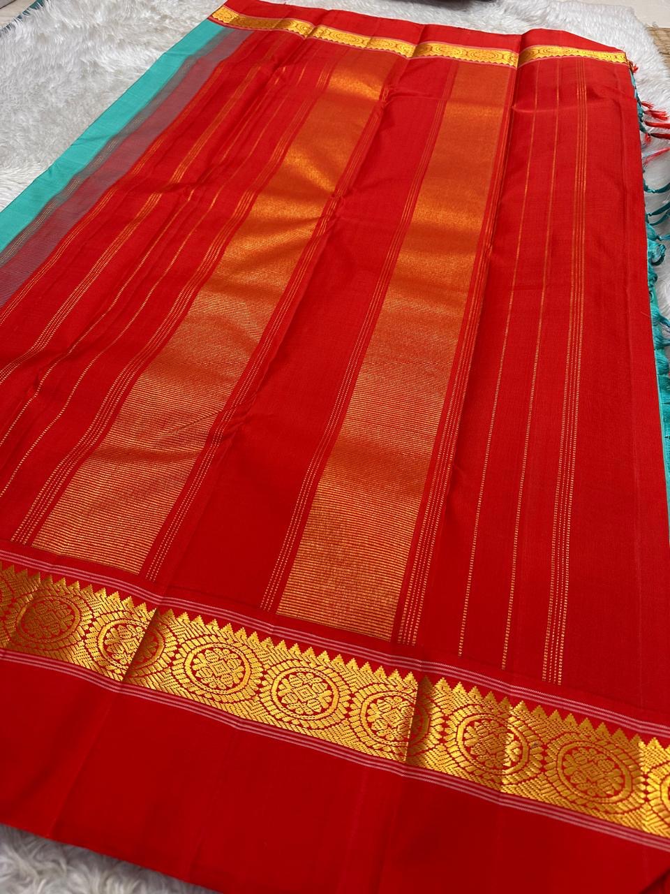 Rama green handloom Kanchipuram silk saree fully spread out, featuring rich red kaal erangina pallu and traditional gold zari motifs.
