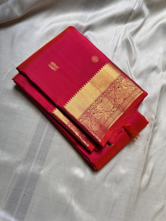 Agnika – Tomato orange shot Red Kanchipuram Silk Saree with Mayil Chakram Butta & Orange Border
Fiery and regal, Agnika is a pure Kanchipuram silk saree featuring a rich red body adorned with intricate Mayil Chakram buttas.