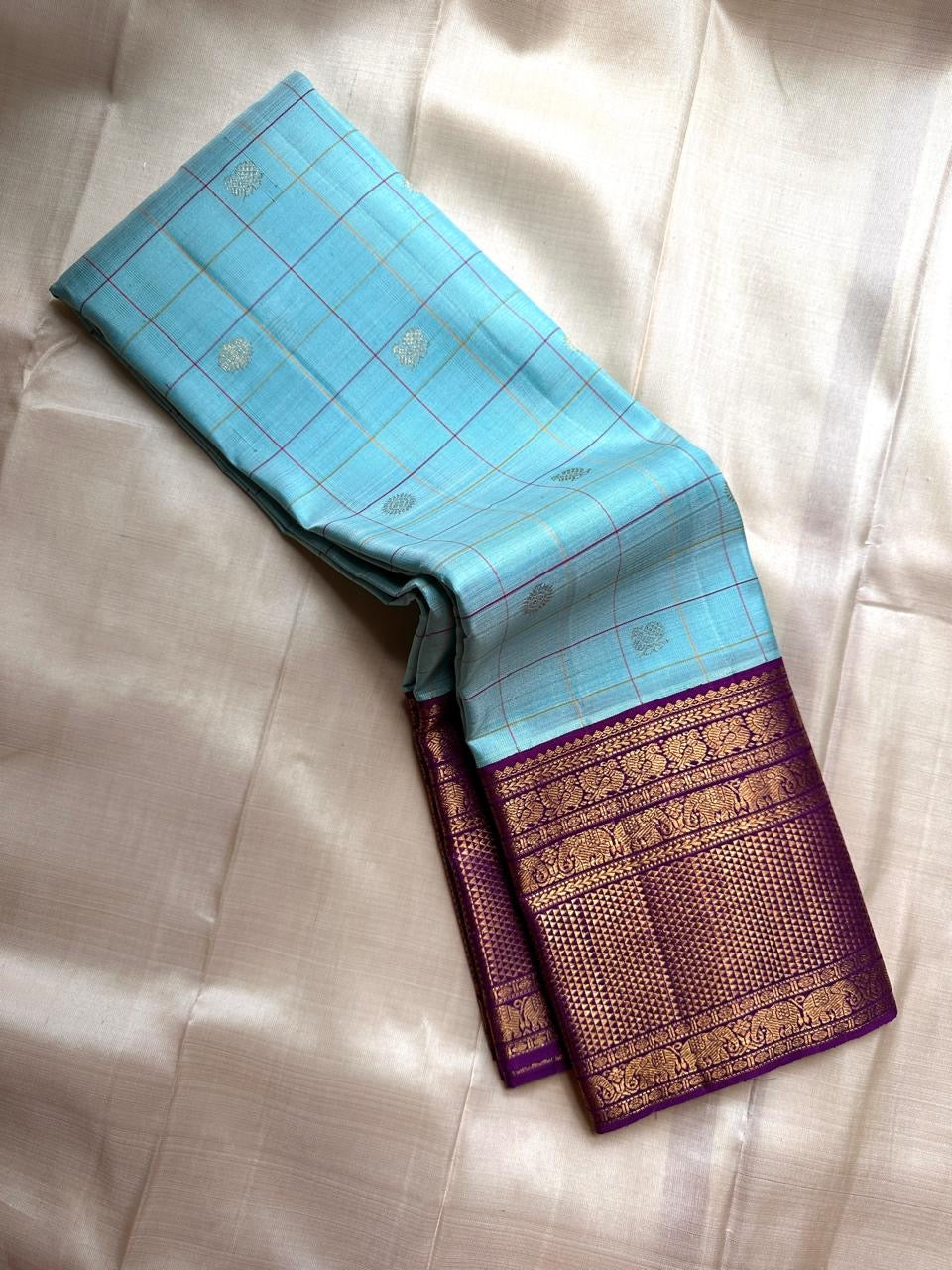 Aakasa Kattam — Pure Kanchipuram Silk Saree
Sky-aqua body with fine kattam checks in lemon and violet, adorned with silver-zari paisley buttas and contrast purple brocade borders.
Silk Mark Certified • Free Shipping within USA • Dispatch in 1 Week • Ships