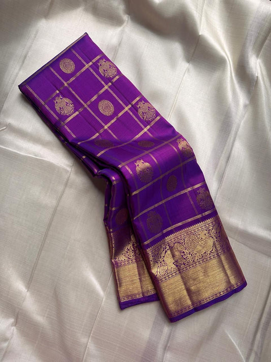 Amethyst Gandaberunda Kamalam – Pure Kanchipuram Silk Saree

Amethyst Purple Body with Zari Kattam Checks & Lotus Buttas

Grand Antique-Gold Borders with Gandaberunda & Peacock Motifs

Purple Zari Brocade Pallu

Silk Mark , ships in 2 weeks