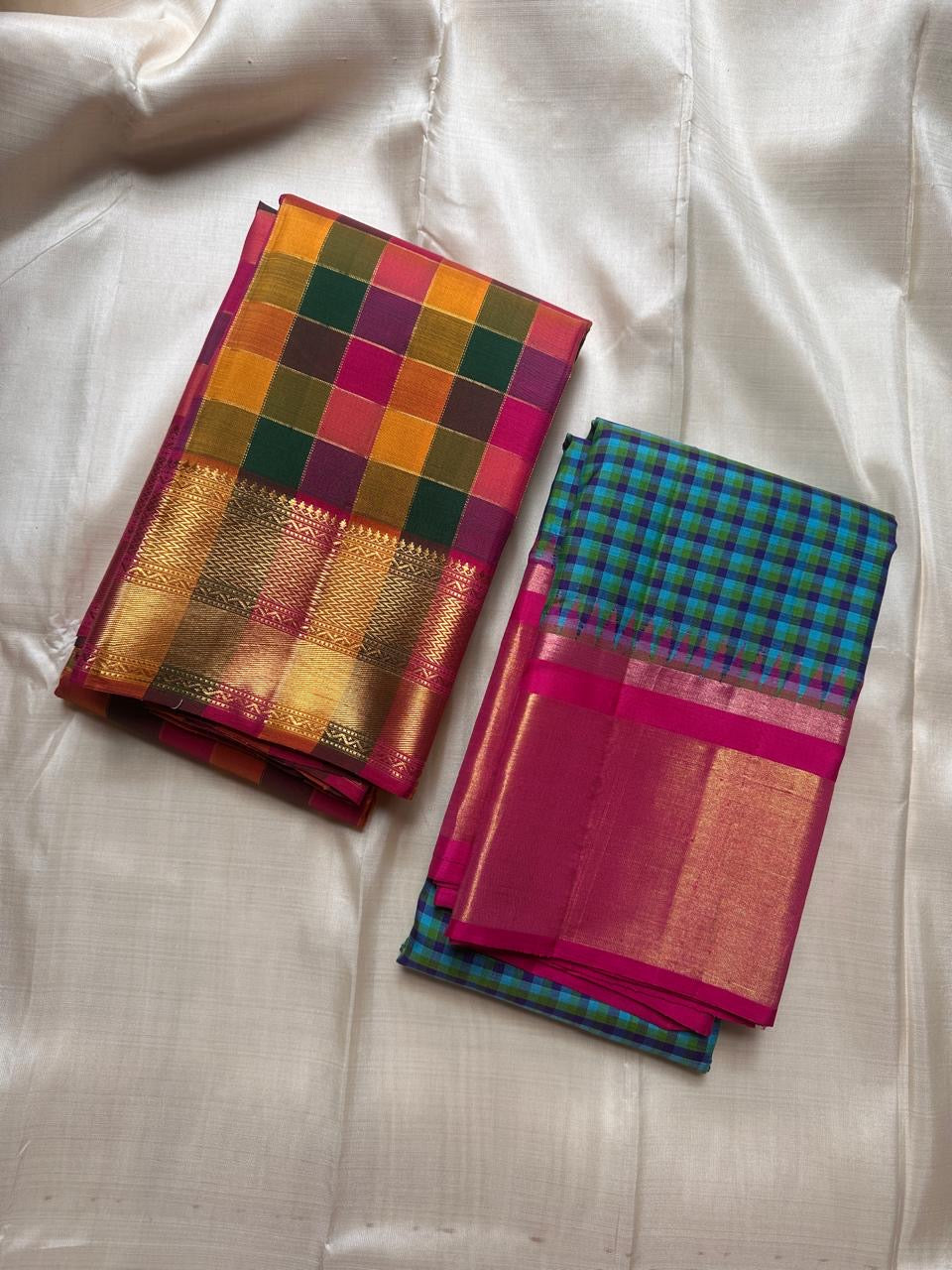 Flat view of blue-green checked body with magenta border and wide gold zari panel, shown in bright natural light