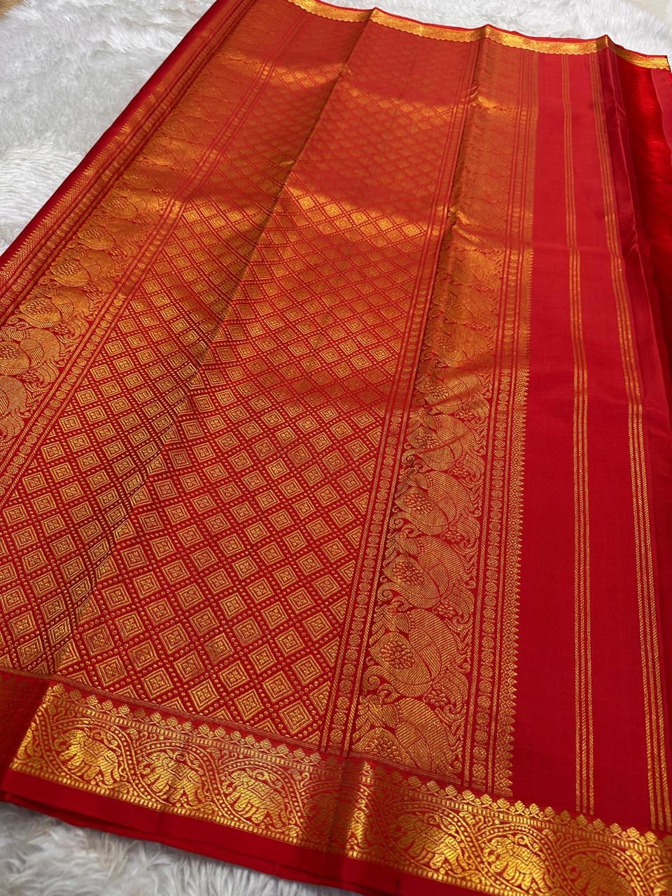 Mahima –red
A luminous red pure silk Kanchipuram drape adorned with delicate baby  kamalam buttas. The petite border features muthu seer and zari-woven elephants with floral vines. Its grand pallu showcases annams, golden grids, and Rudhraksham seer.