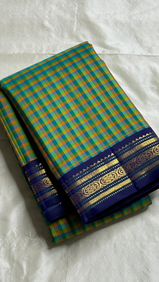 Mayil Pachai Kattam
Pure Kanchipuram Silk Saree + blouse Peacock Green & Mustard pattani Checks
Royal blue korvai borders with 2g floral zari detailing
Fully stitched embroidered blouse
Ships in 2 weeks free silk mark certified