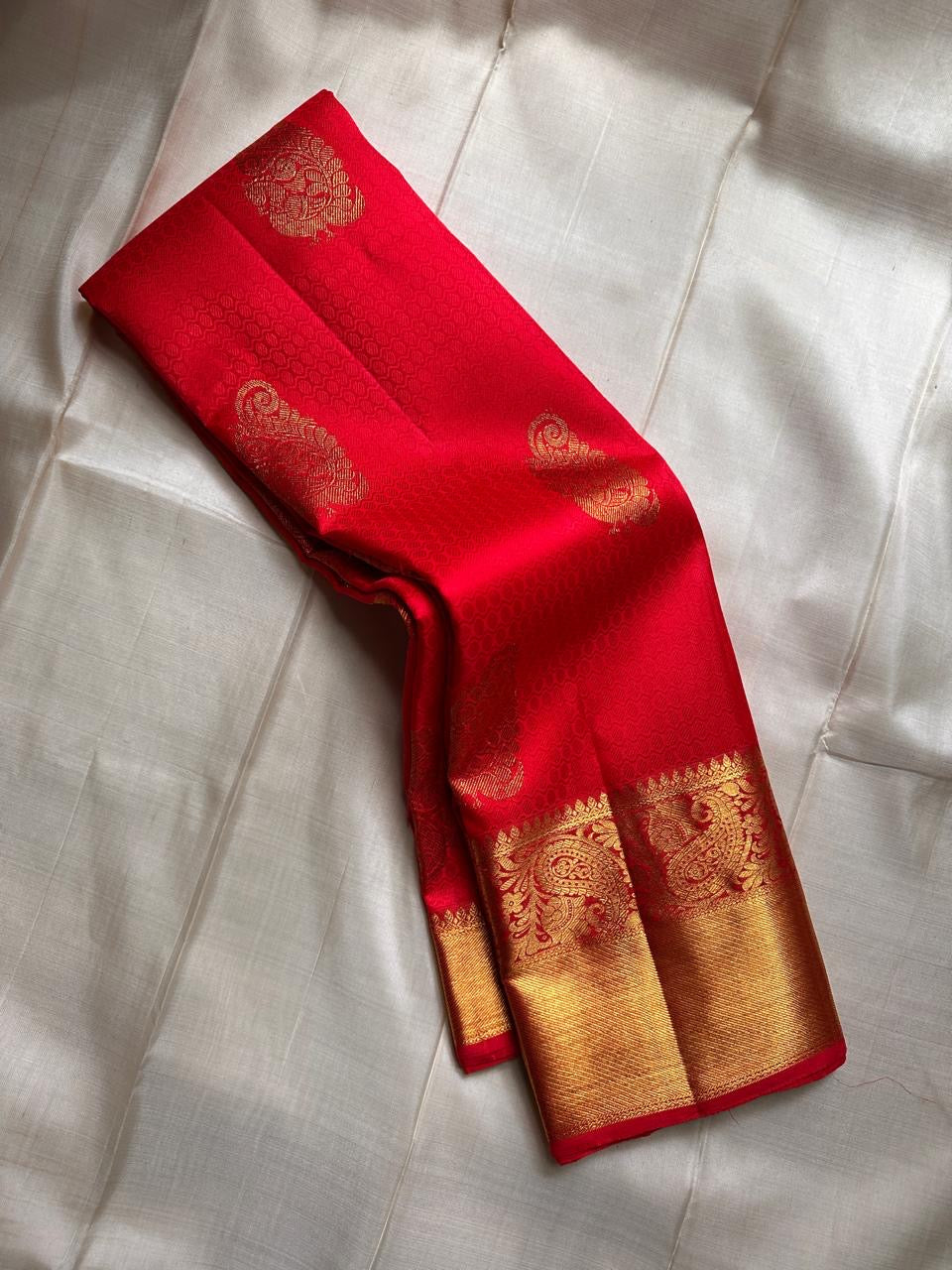 A traditional Kanjivaram (Kanchipuram) silk saree, vibrant red orange peacock floral motifs bavanji border and ornate grid motif Pallu