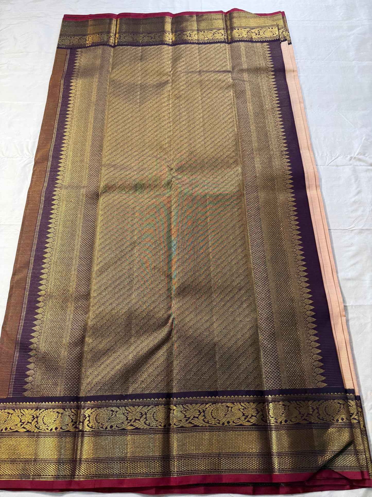 Sandhya 🌅 – Sun-Kissed Beige Kanchipuram Silk Saree with Subtle Vairaoosi Gold Filament ✨, Deep Purple Peacock Diamond-Pettu Zari Border 🦚, Deep Maroon Selvedge, and Zari-Embellished Pallu with Arai Maadam & Khalasam Motifs 🌿💛