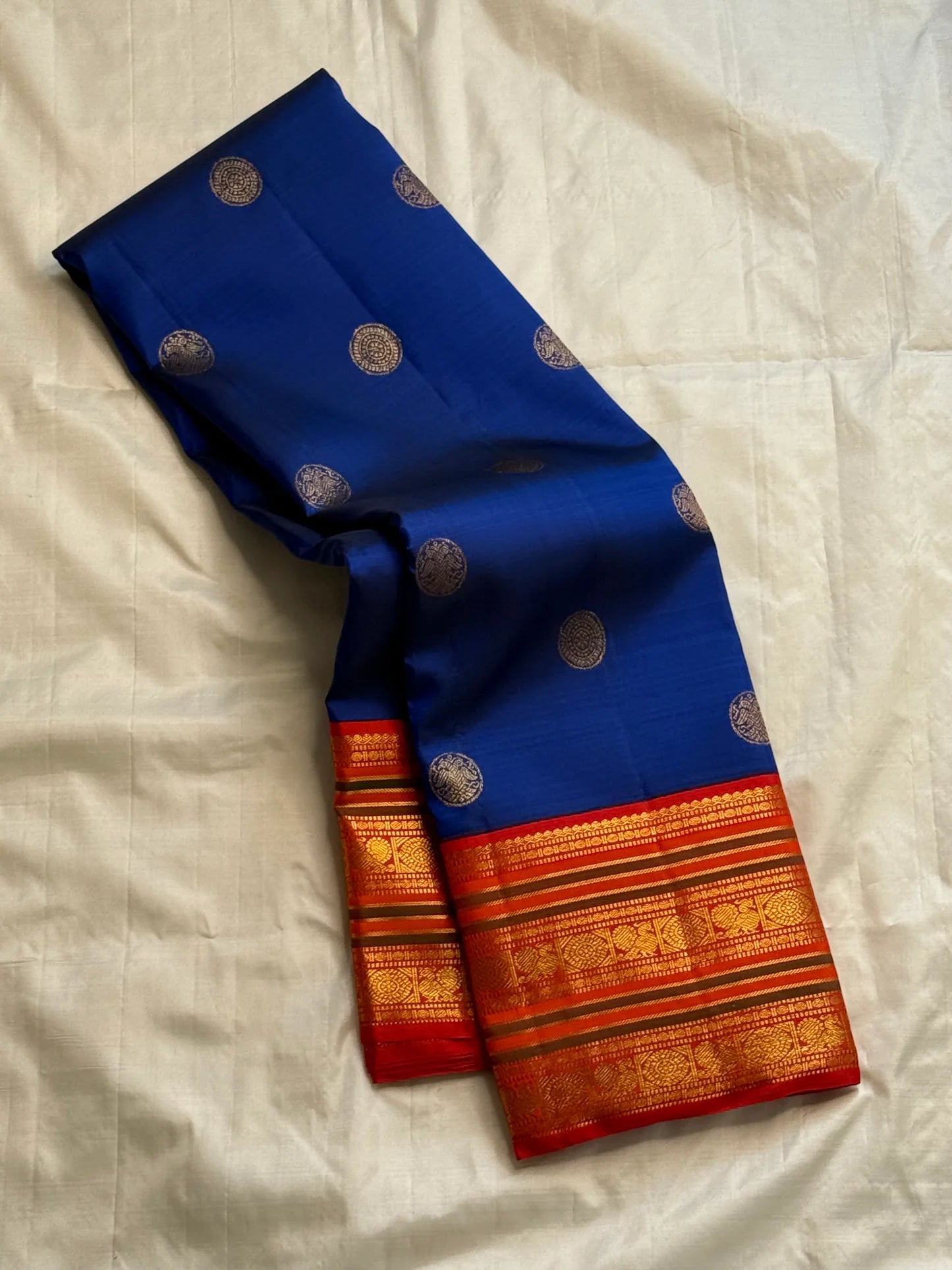 Royal blue Kanchipuram silk saree folded with coin buttas and red zari woven border