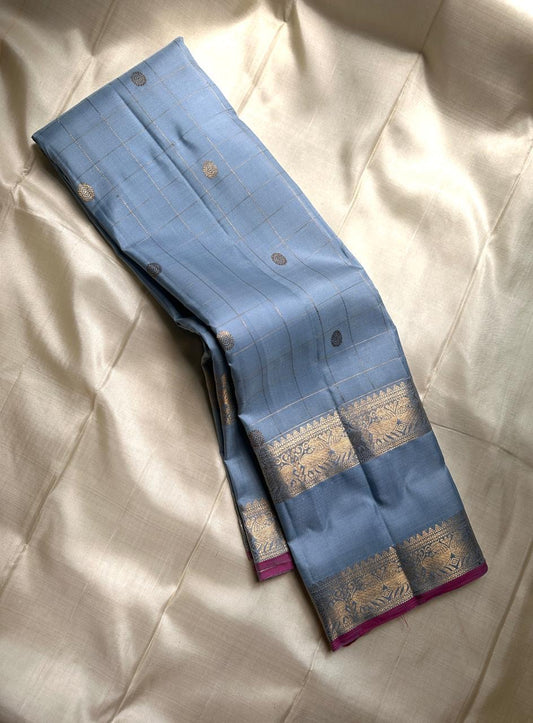 Fuchsia in Sky – Pure Silk Kanchipuram Saree
Sky Blue Body with Gold Kattam Checks & Petite Buttas
Fuchsia Contrast Petni Pallu with Zari Reku Stripes
Wide Gold Zari Border with Peacock & Temple Motifs
Silk mark certified, ships in 2 weeks