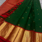 Close view of emerald green silk body with small gold zari buttas and contrast red border