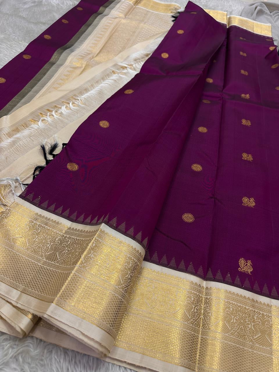 Varuni — Deep Purple & Magenta Shot Kanchipuram Silk Saree
Gold Zari Peacock Motifs on Luxurious Pure Silk
Antique Gold Korvai Border with Gandaberunda Design
Intricate Temple-Inspired Pillayar Moggu Detailing
Silk mark certified