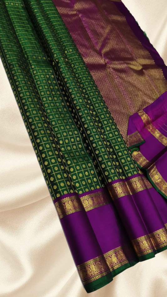 An heirloom-worthy drape woven in the finest 2G pure silk, this traditional Kanchipuram saree brings together the timeless beauty of zari buttas and checks in a rich green body. The contrast purple  rettapet border stands bold and elegant