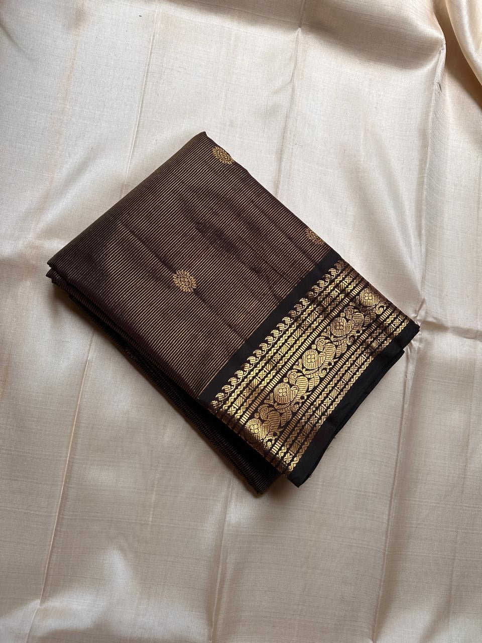 Kohl Swarna — silk mark certified lightweight saree 
Deep kohl brown body with fine pinstripes and gold rosette buttas, framed by antique-gold zari borders and grand paisley brocade pallu• free shipping eithin usa  two weeks