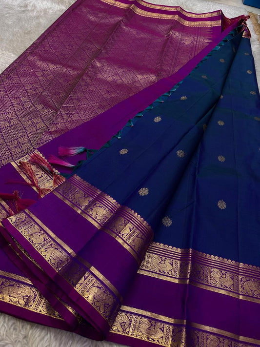 Purple Allure – Pure Kanchipuram Silk Saree
Peacock-blue body adorned with petite zari floral buttas 🌸
Contrast royal-purple border with grand elephant procession 🐘
Rich zari brocade pallu in floral motifs ✨

Silk Mark Certified, delivery in 2 weeks