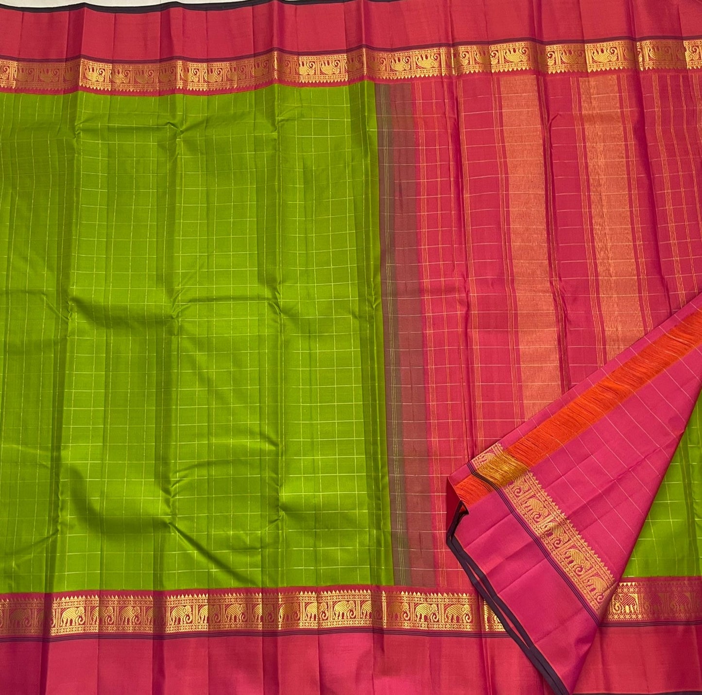 Valli Pachai – Kanchipuram Pure Silk Saree

Parrot-green body in kattam (grid) checks with subtle zari lines

Korvai contrast rani-pink borders featuring gaja (elephant) procession & temple reku motifs

Rich rani-pink zari pallu with vertical bands