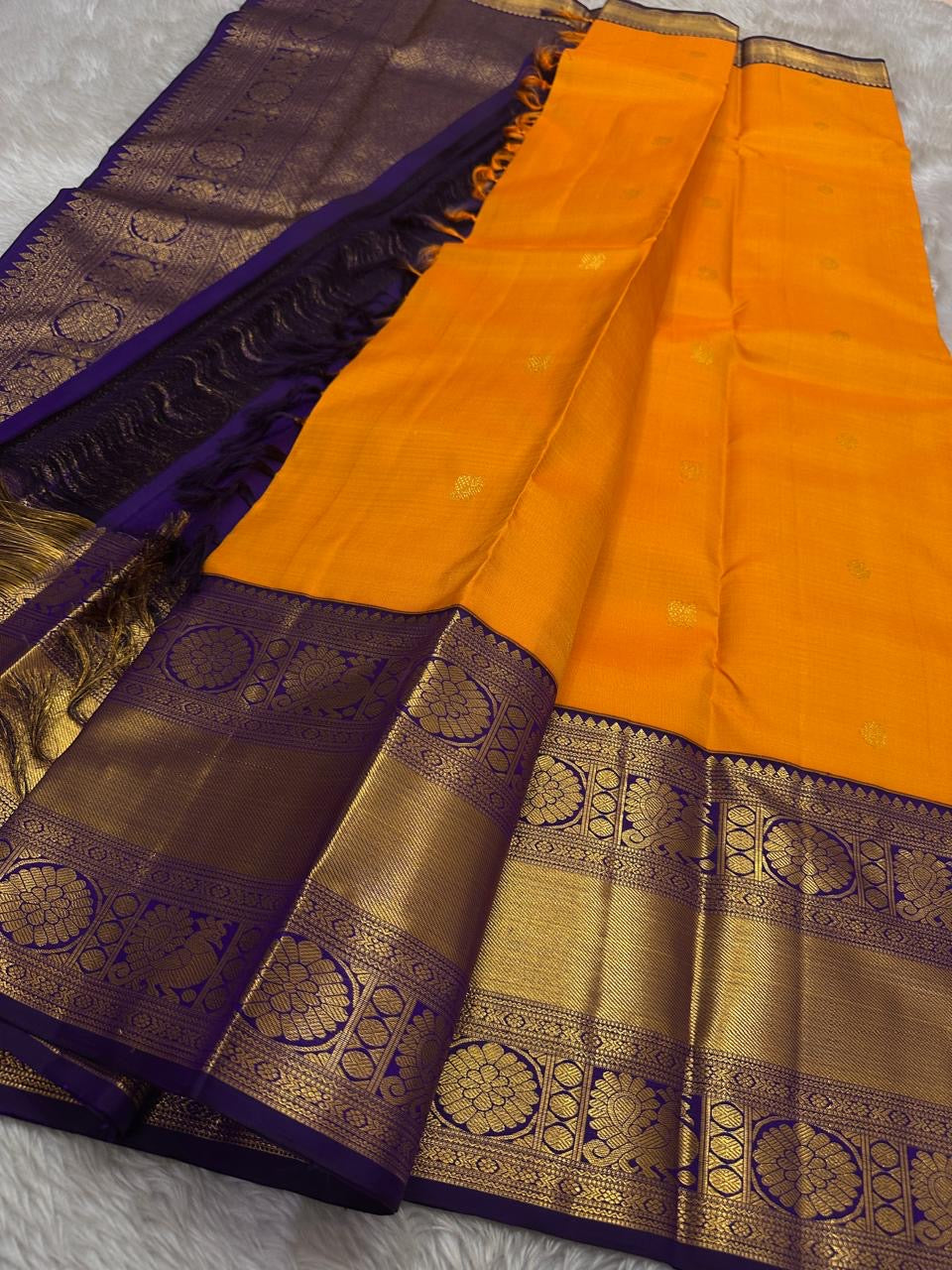 This Maambazha yellow Kanchipuram silk saree features zari mayil buttas and a deep blue rettapet border with kamalam motifs — a timeless blend of tradition and grace.