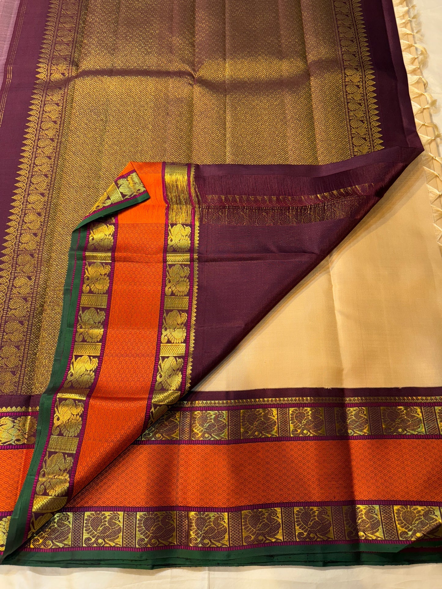 Pallu view of pure Kanchipuram silk saree showing deep maroon purple zari woven pallu field with gold patterning and rust orange border accents