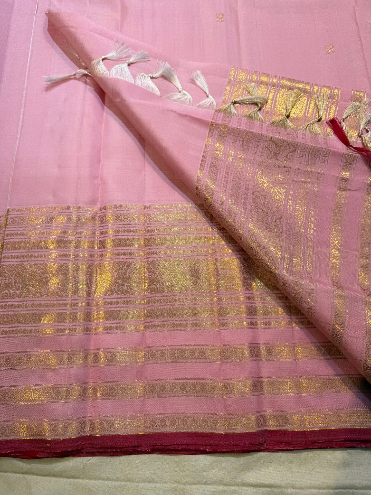 Detailed gold zari elephant and peacock motifs on the blush pink Varisaipet self border
